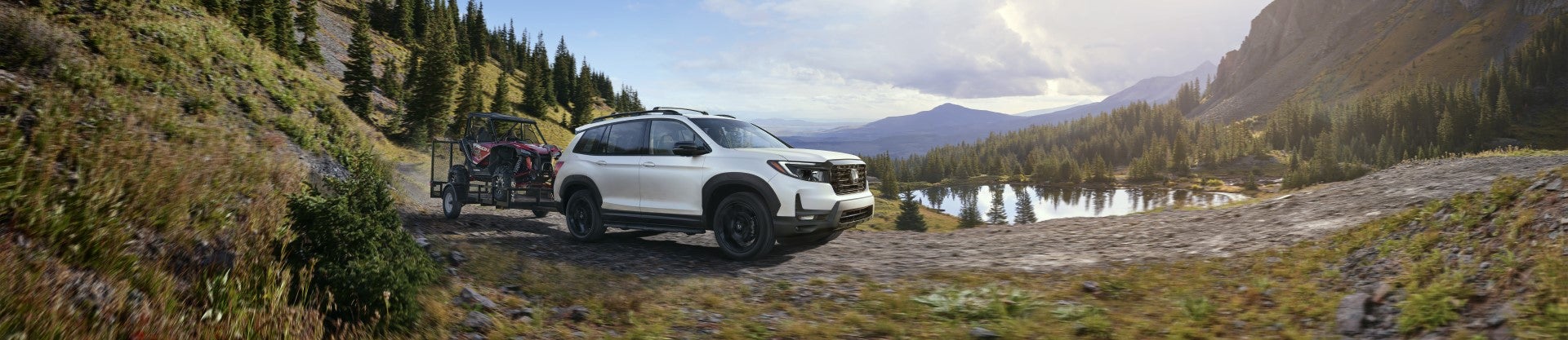 Honda SUV hauling trailer down moutain trail